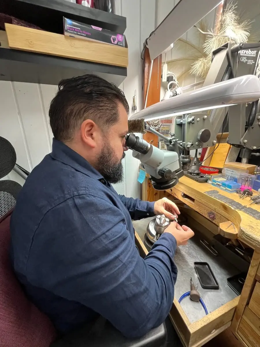 Adriano at his bench in Boston, working on a piece under a microscope.